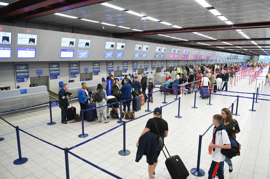 airport security line of people looking to check in their baggages in a middle of a medium density airport with guide lines and people shown is motion